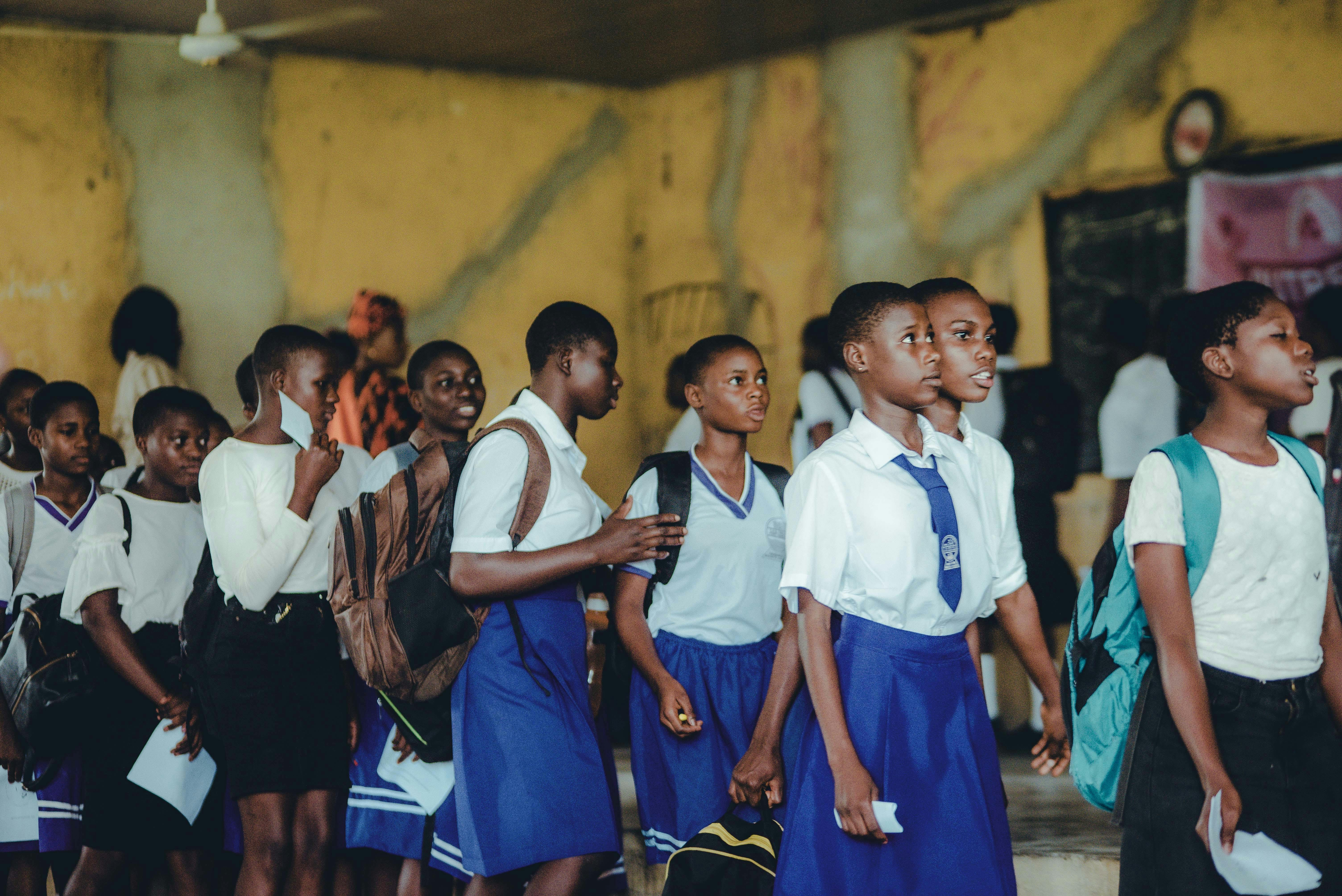 Group of African high school girls in uniform during class transition indoors.
